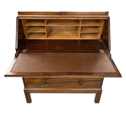 1133 - A mid century military War Office mahogany mahogany bureau bookcase, the upper section with a pair o... 