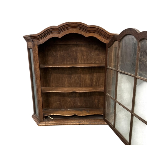 1134 - A Queen Anne style oak hanging cabinet with astragal glazed door enclosing a shaped shelved interior... 