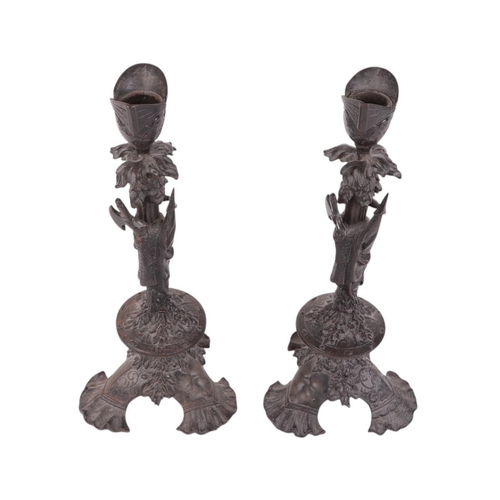 517 - A pair of late 19th century cast iron candlesticks decorated with axes and an inverted helmet; toget... 