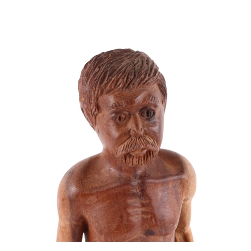 562 - A folk art wooden carving of a man with naked torso, breeches and open toed sandals, 38cms high.