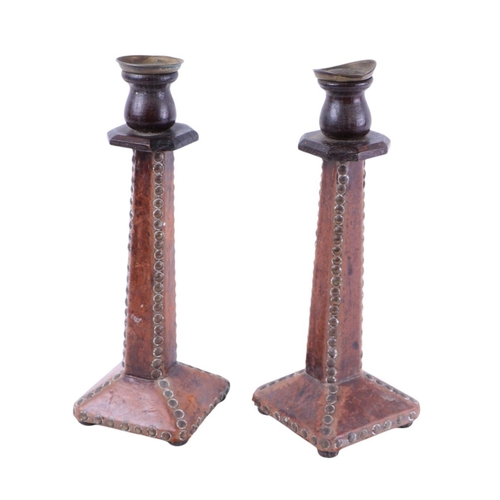 581 - A pair of Arts & Crafts oak leather covered brass studded candlesticks, 32cms high; together with tw... 