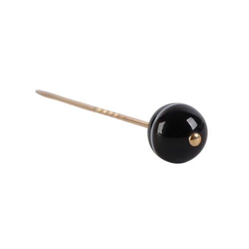 831 - A yellow metal stick pin with agate ball terminal, 8cms long, 7.2g.