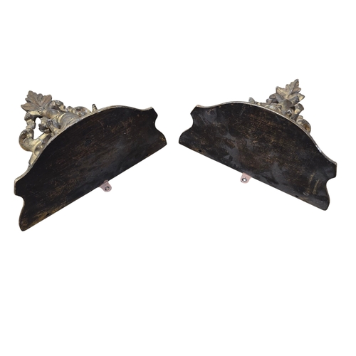 569 - A pair of 19th century carved giltwood shelf brackets with winged cherub decoration, 24cms high (2).