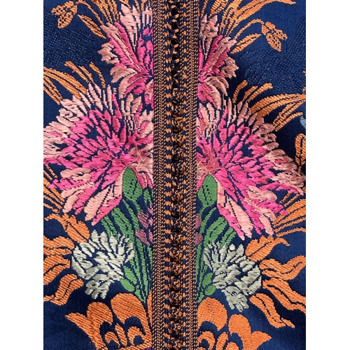 163 - A Moroccan embroidered kaftan decorated with flowers on a blue ground, signed.