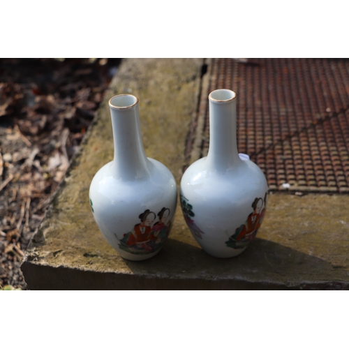 956 - A pair of Chinese famille rose bottle vases decorated with figures, 17cms high.