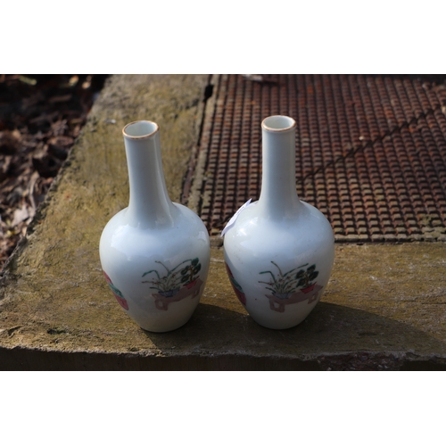 956 - A pair of Chinese famille rose bottle vases decorated with figures, 17cms high.