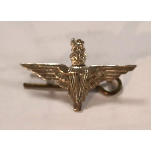 55 - A group of WWII cloth badges and cap badges to include Special Air Service cap badge and cloth badge... 