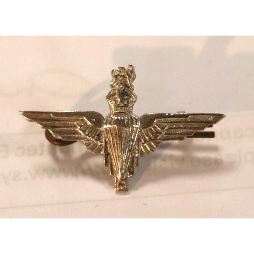 55 - A group of WWII cloth badges and cap badges to include Special Air Service cap badge and cloth badge... 