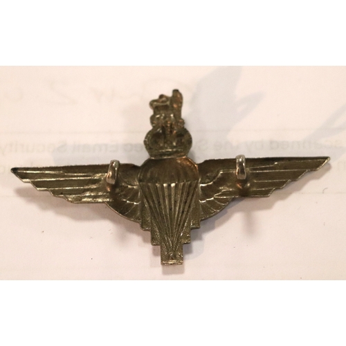 55 - A group of WWII cloth badges and cap badges to include Special Air Service cap badge and cloth badge... 