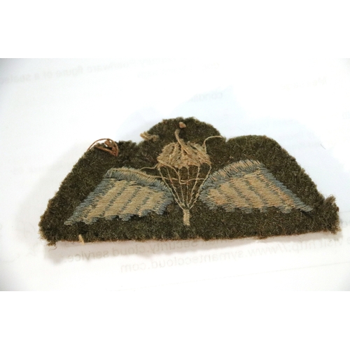 55 - A group of WWII cloth badges and cap badges to include Special Air Service cap badge and cloth badge... 