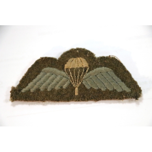 55 - A group of WWII cloth badges and cap badges to include Special Air Service cap badge and cloth badge... 