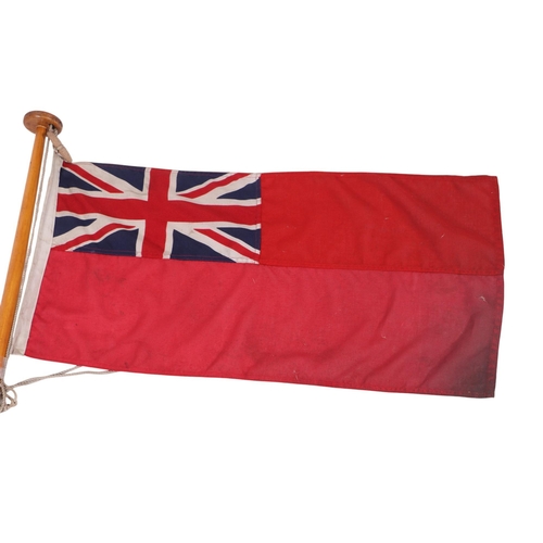 116 - A cotton Union Jack Ensign flag mounted on a pole. 90 by 44cm