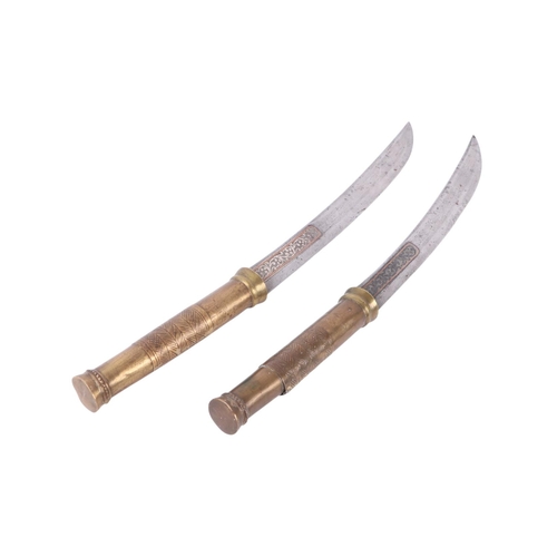 83 - An early 20th century pair of Burmese Dha knives with brass worked handles, the steel blades with si... 