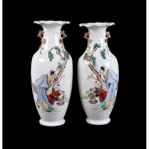 709 - A pair of Chinese famille rose vases decorated with figures in a landscape, 28cms high.