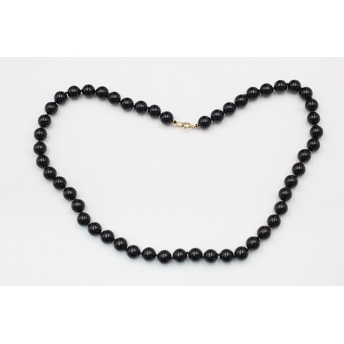 308 - 9ct gold clasped polished black onyx bead necklace 35 grams gross