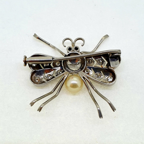 1008 - White metal fly, a body of metal and pearl with open work
diamond set wings and two ruby eyes.