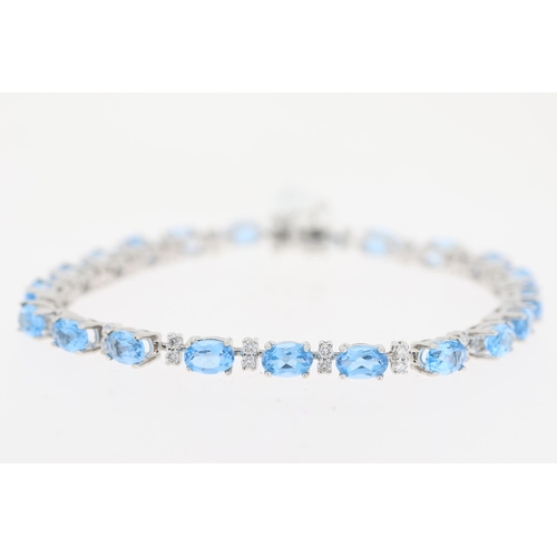 1010 - 18ct white gold blue topaz and diamond line bracelet. Oval cut blue topaz stones with round brillian... 