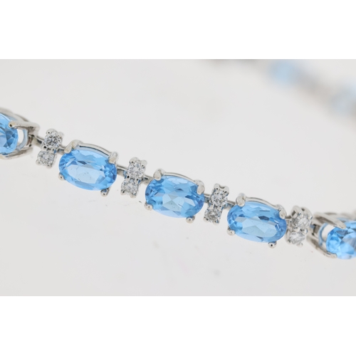 1010 - 18ct white gold blue topaz and diamond line bracelet. Oval cut blue topaz stones with round brillian... 