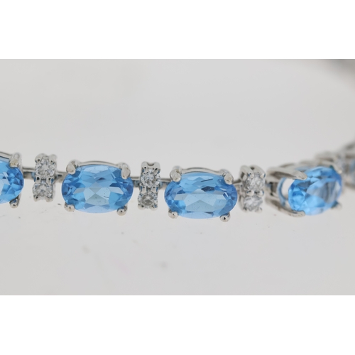 1010 - 18ct white gold blue topaz and diamond line bracelet. Oval cut blue topaz stones with round brillian... 