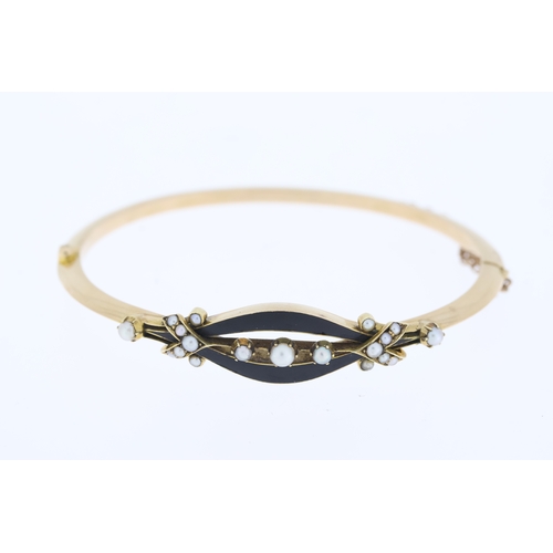 1000 - Tests 15ct Victorian enamel and pearl bangle, hinged with a safety chain.