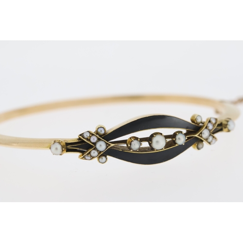 1000 - Tests 15ct Victorian enamel and pearl bangle, hinged with a safety chain.