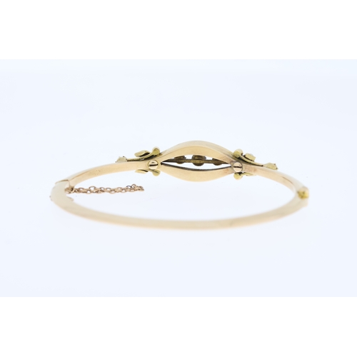 1000 - Tests 15ct Victorian enamel and pearl bangle, hinged with a safety chain.