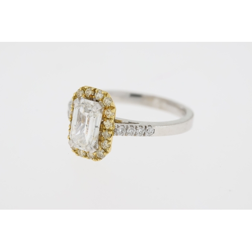 1008 - Stamped 18K and partial hallmark. An emerald cut diamond ring with a halo of yellow diamonds. Centra... 