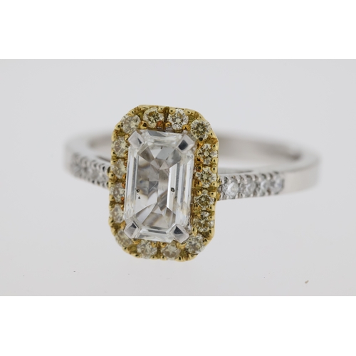 1008 - Stamped 18K and partial hallmark. An emerald cut diamond ring with a halo of yellow diamonds. Centra... 