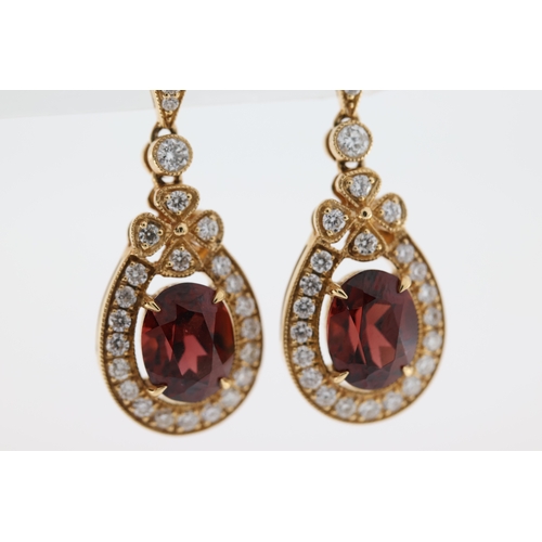 1003 - A pair of 18ct garnet & diamond drop earrings.