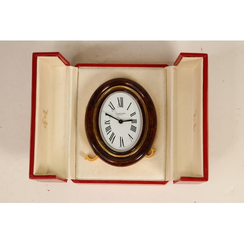 175 - A Cartier faux tortoiseshell oval cased desk/bedside alarm clock. Ref '7509 - 20863'. A white oval d... 