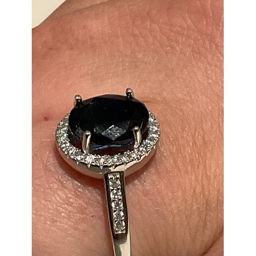 81 - Silver ring stamped 925 with large central deep blue stone surrounded by Cz stones and with cz on sh... 