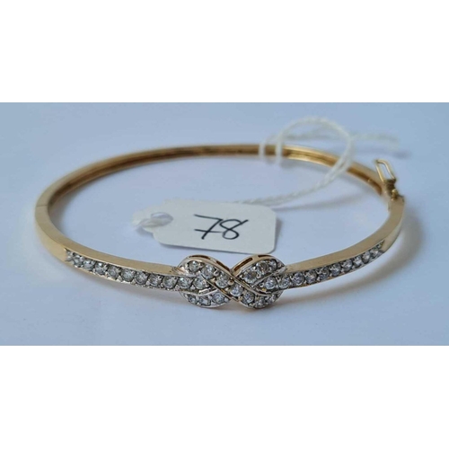 78 - An attractive 9ct hinged bangle set with CZ ribbon bow design 8.4g inc