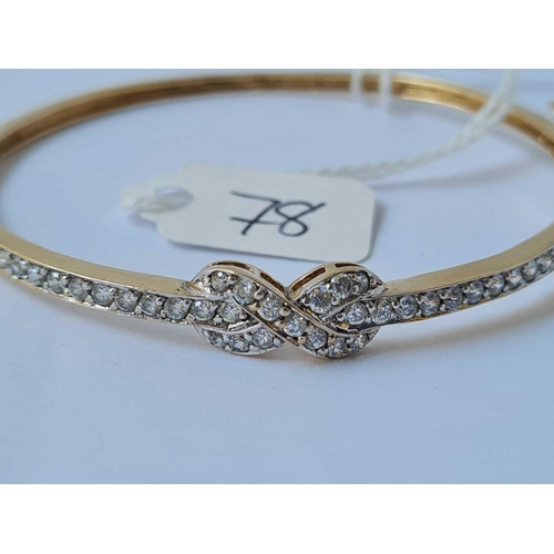 78 - An attractive 9ct hinged bangle set with CZ ribbon bow design 8.4g inc