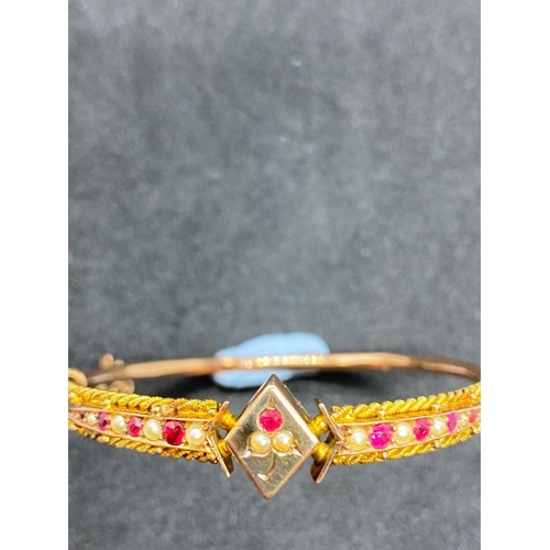 404 - A ROSE GOLD ATTRACTIVE BANGLE MOUNTED WITH RUBY AND PEARL PANELS OF LOZENGE SHAPED CENTRE SET IN 9CT... 