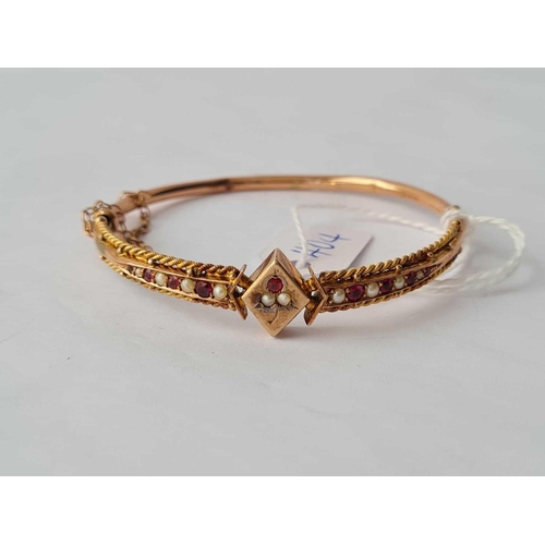 404 - A ROSE GOLD ATTRACTIVE BANGLE MOUNTED WITH RUBY AND PEARL PANELS OF LOZENGE SHAPED CENTRE SET IN 9CT... 