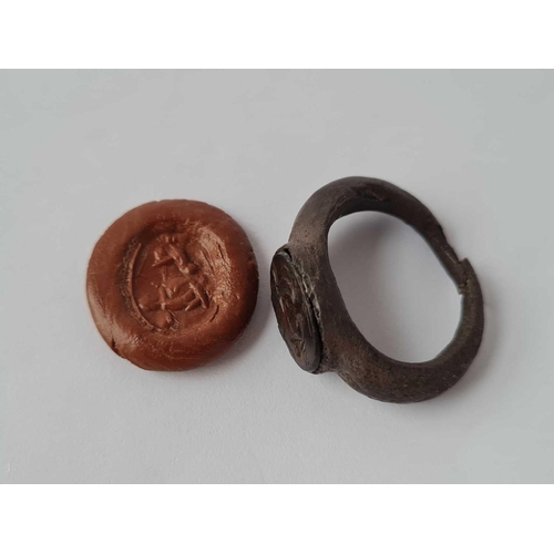 232 - A ANTIQUE ROMAN BRONZE SIGNET RING SET WITH A CARVED INTAGLIO CARNELIAN DEPICTING A WING CHERUB DRIV... 