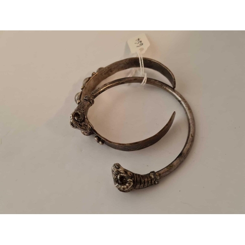 654 - Two white metal torque bangles one with rams heads ends