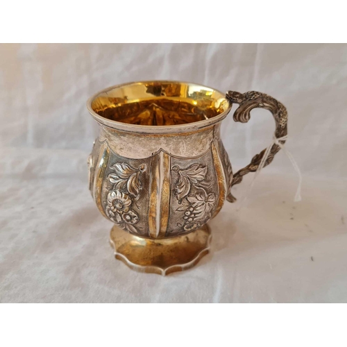 722 - A parcel gilt Georgian Christening mug with embossed panels and Lizard shape cast handle, 3.5