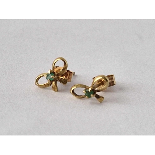 246 - A pair of emerald set bow shaped ear studs 9ct