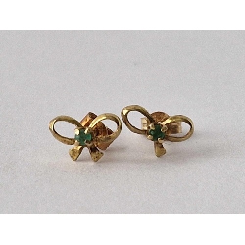 246 - A pair of emerald set bow shaped ear studs 9ct