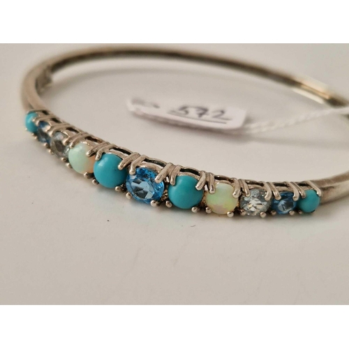 572 - A silver bangle with assorted stones