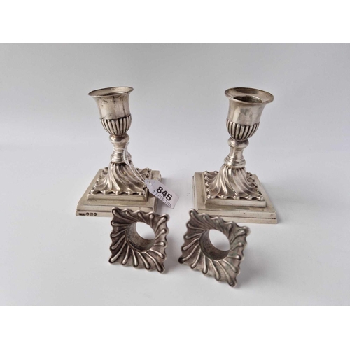 845 - A pair of candlesticks the square bases with swirl decoration and detachable nozzles, 4.5