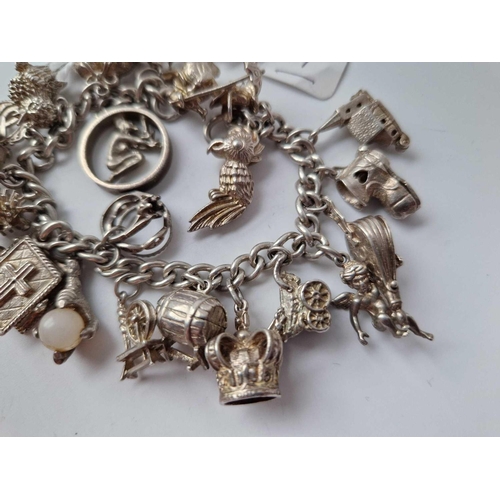 77 - A heavy silver charm bracelet with 20 silver charms 85g