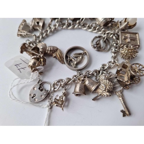 77 - A heavy silver charm bracelet with 20 silver charms 85g