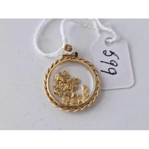 599 - A circular gold pendant with gold flakes 14ct gold 2 gms inc.