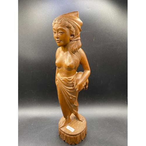 1822 - An Asian carved wood figure of a lady with a piglet, 17 inches high