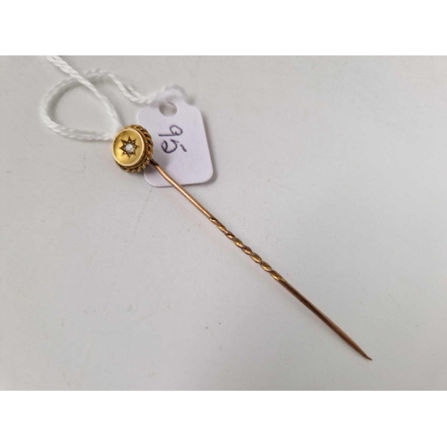 95 - A gold topped stick pin, set with a diamond