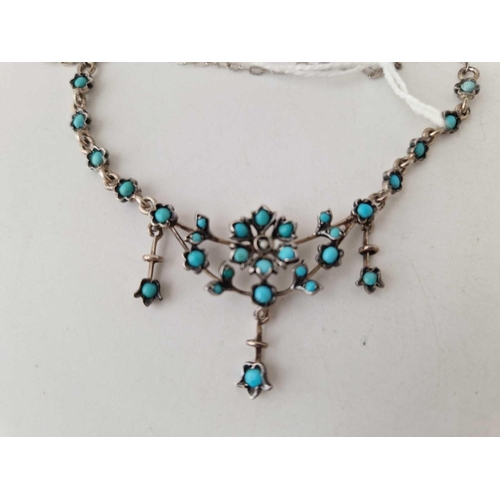 113 - A silver turquoise set fringe necklet with flower design centre