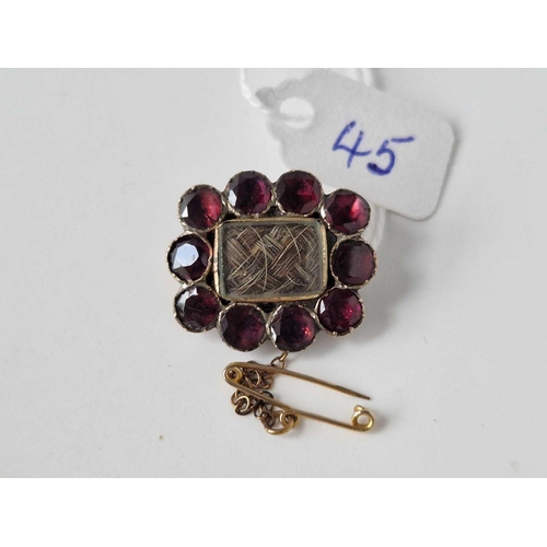 45 - A Georgian flat cut garnet memorial brooch with crystal viewing centre and safety chain