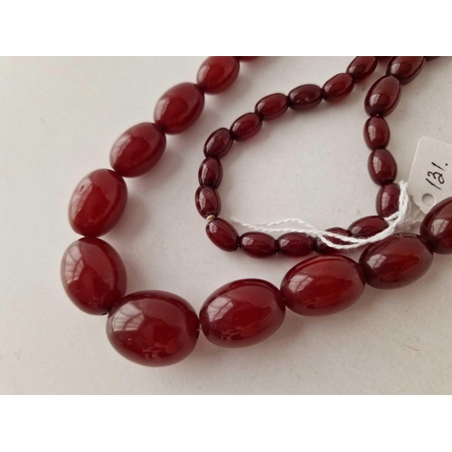 131 - A STRING OF CHERRY AMBER BEADS 26 INCH 64.6 GMS